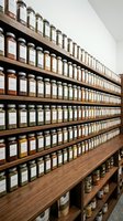 Organized spice rack with hundreds of labeled glass jars containing herbs and spices on wooden shelves in modern pantry storage system for culinary use.