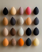 Makeup sponges in various colors and textures arranged in neat rows on neutral background. Professional beauty blending tools collection showing different shapes and finishes.