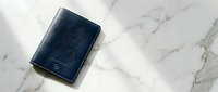 Navy blue leather wallet on white marble surface for business and finance concepts.