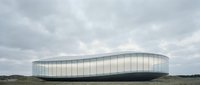 Futuristic glass and steel oval building with curved architecture set against cloudy sky and open landscape, suitable for corporate, technology, and modern design projects.