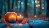 Orange pumpkin with glowing candles and autumn leaves on rustic surface against blurred forest background with magical bokeh lights at dusk.