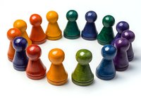 Colorful wooden game pieces in rainbow hues arranged on white background. Vibrant pawn-shaped tokens for board games, educational activities, and crafts.