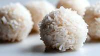 Coconut balls coated with shredded coconut flakes, ideal for confectionery, bakery, and food styling projects.