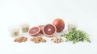 Healthy breakfast ingredients with grapefruit, nuts, seeds and herbs arranged on white background for nutritious meal preparation and clean eating.