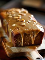 Chocolate loaf cake with caramel glaze and peanut toppings on wooden board, perfect for bakery, dessert, and food photography projects.