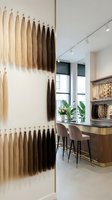 Professional hair extension salon interior with color samples displayed on wall showcasing blonde to brunette shades for beauty business styling services.