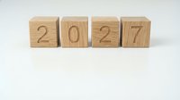 Four wooden blocks with engraved numbers spelling 2027 arranged in a row on a white surface, perfect for new year concepts.