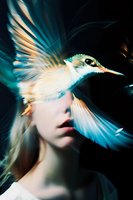 Surreal artistic portrait with flying hummingbird in motion creating ethereal overlay effect against dark background, combining nature and feminine elements.
