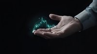 Male hand in business suit holding glowing green stock market chart graph floating above palm against dark background, representing financial growth and investment.