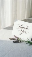 Elegant thank you card with calligraphy script beside fresh lavender sprigs on soft linen, styled for wedding stationery and gratitude concepts.