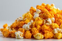 Colorful mix of cheese and caramel popcorn on white surface against gray background, popular snack for movie nights and parties.