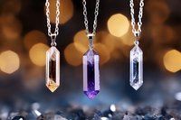 Three elegant crystal pendant necklaces with pointed gemstones in pink, purple and clear colors hanging on silver chains against warm bokeh background.