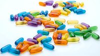 Colorful vitamin capsules and pills scattered on white background. Health supplements in various shapes and colors isolated for medical design.