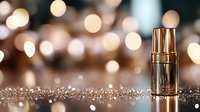 Luxury gold cosmetic serum bottle on glittery surface with soft bokeh lights background creating elegant atmosphere for beauty product photography.