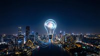 Glowing light bulb with brain inside floating above illuminated city skyline at night representing innovation and smart urban technology solutions.