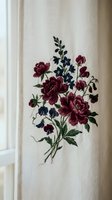 Elegant floral embroidery on white linen fabric featuring burgundy roses and blue wildflowers in vintage botanical style for home decor and textile design.