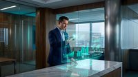 Professional businessman in dark suit using smartphone in modern glass office with city view and contemporary interior design for corporate communications.