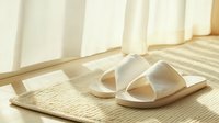 White cozy home slippers on beige carpet near window with sunlight and shadows creating peaceful morning atmosphere for lifestyle and comfort concepts.