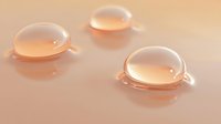Glossy rose gold liquid drops on peach colored surface creating elegant minimal composition with soft reflections and shadows. Suitable for cosmetic advertising.