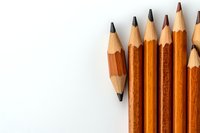 Wooden graphite pencils arranged on white background with copy space. Minimalist composition showing sharpened pencil tips for creative and educational concepts.