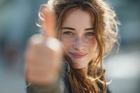 Young blonde woman with freckles giving thumbs up gesture, smiling at camera with positive attitude and confident expression for motivational content.