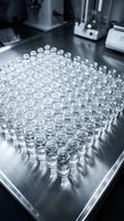 Empty glass vials arranged in rows on laboratory equipment surface for pharmaceutical research and medical testing applications.