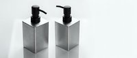 Two modern stainless steel soap dispensers with black pump tops on reflective surface for contemporary bathroom and kitchen design.