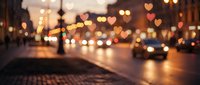 Romantic city street at night with heart-shaped bokeh lights from traffic and streetlights creating dreamy Valentine atmosphere on wet pavement.