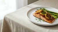 Grilled salmon fillet with lemon slices and asparagus on white plate, fine dining presentation for restaurant menus and culinary content.