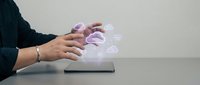 Person interacting with holographic brain projection from tablet device showcasing futuristic medical technology and digital healthcare innovation.