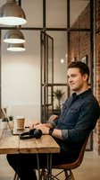 Young Caucasian businessman working on laptop in modern industrial office space with exposed brick walls and pendant lighting for coworking concepts.