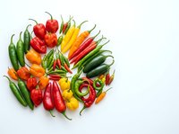 Assorted fresh chili peppers and hot peppers arranged on white background, isolated for cooking, recipe, and culinary design projects.