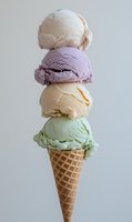 Stacked scoops of colorful ice cream in waffle cone featuring vanilla, berry, cream and mint flavors against light background, minimal summer dessert composition.