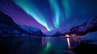 Aurora borealis dancing over snow-covered mountains and frozen lake at night, northern lights display with vibrant green and purple colors reflecting on water.