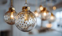Elegant glass Christmas ornaments with gold polka dot pattern hanging against soft bokeh background for holiday decor.