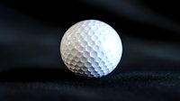 White golf ball with dimpled surface on dark textured background for sports equipment and recreational activity concepts.