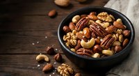 Mixed nuts assortment in dark bowl on rustic wooden table with cashews, walnuts, pecans, almonds and hazelnuts for healthy snacking and cooking.
