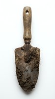 Antique wooden shovel with weathered handle and soil-encrusted metal blade, showing signs of age and extensive use in gardening or archaeological work.