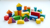 Colorful wooden building blocks set with geometric shapes including cubes, triangles, cylinders and rectangles for educational play and learning activities.