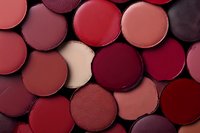 Flat lay of assorted matte eyeshadow and blush makeup palettes in red, burgundy, and nude tones, forming a full cosmetic background.