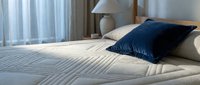 Comfortable bed with navy blue pillow and striped bedding in modern bedroom interior with natural light from window and contemporary decor.