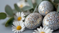 Decorative Easter eggs with metallic gold pattern and white daisies on soft background create festive spring composition for holiday celebration.