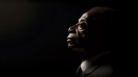 Dramatic side profile portrait of mature African American man against dark background with rim lighting highlighting facial features and expression of contemplation.