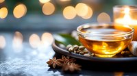Warm herbal tea in glass cup with spices and bokeh lights creating cozy evening atmosphere for relaxation and wellness moments.