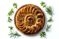 Spiral shaped savory bread with herbs and spinach filling on wooden board, decorated with fresh rosemary and parsley leaves on white background.