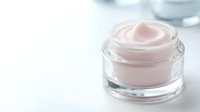 Open jar of pink moisturizing cream or facial skincare product on white background, ready for cosmetics, beauty, and wellness design projects.