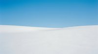 Minimalist white sand dunes landscape with clear blue sky, suitable for backgrounds, travel promotions, and desert-themed design projects.