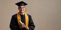 Smiling graduate in black cap and gown with gold stole holding diploma against neutral background, representing academic achievement and educational success.