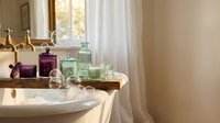Elegant vintage bathroom interior with colorful glass bottles and brass fixtures creating luxurious spa atmosphere for home decor and wellness design.