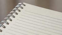 Spiral bound notebook with blank lined pages, close-up view on blurred background, ready for notes, planning, and creative writing.